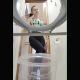 A pretty blonde girl records herself taking a massive shit into a plastic container while sitting on a potty chair. Vertical format video. About 2 minutes.